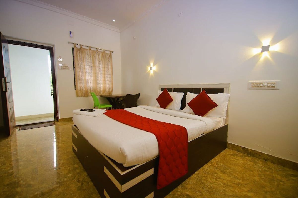 Una habitación de hotel con una cama, una silla, una mesa y una puerta.