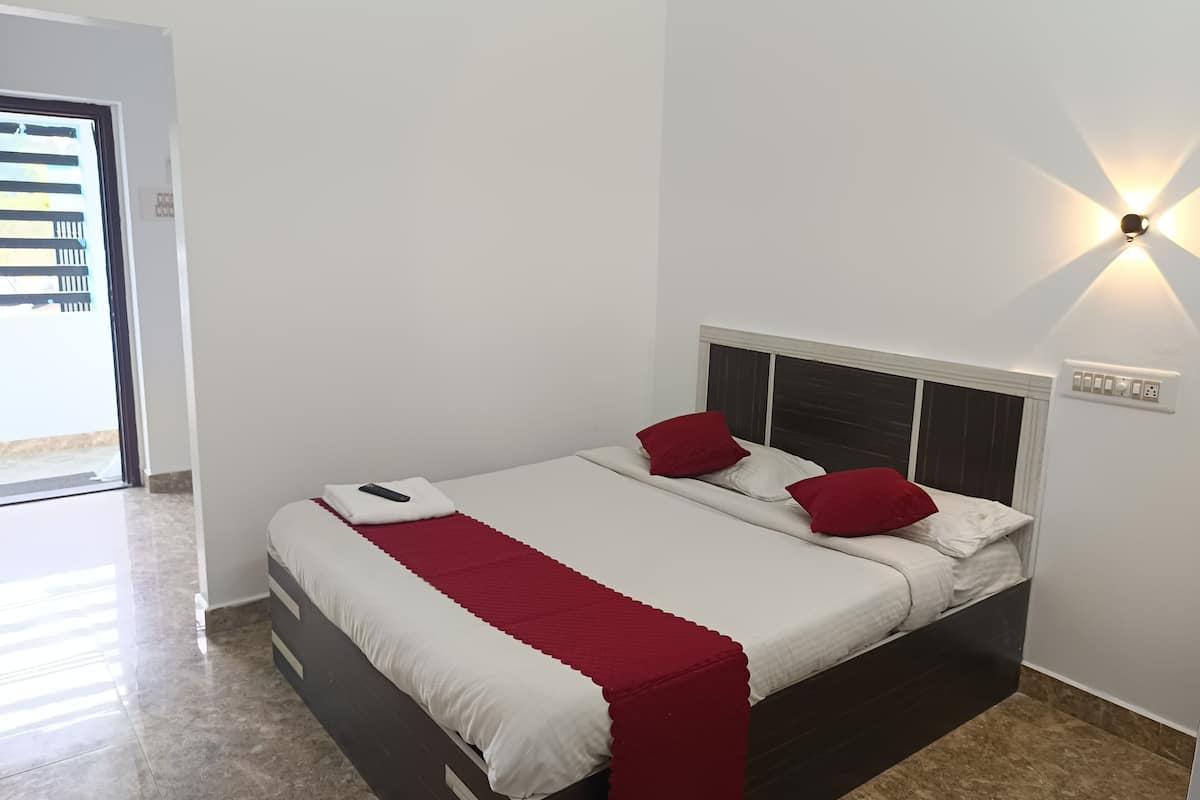 Una cama bien tendida con ropa de cama blanca y roja, un cabecero y una lámpara fijada a la pared.
