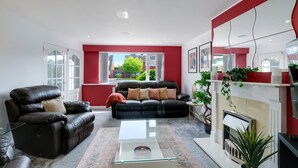 A modern living room with a black leather sofa, a glass coffee table, and a fireplace.