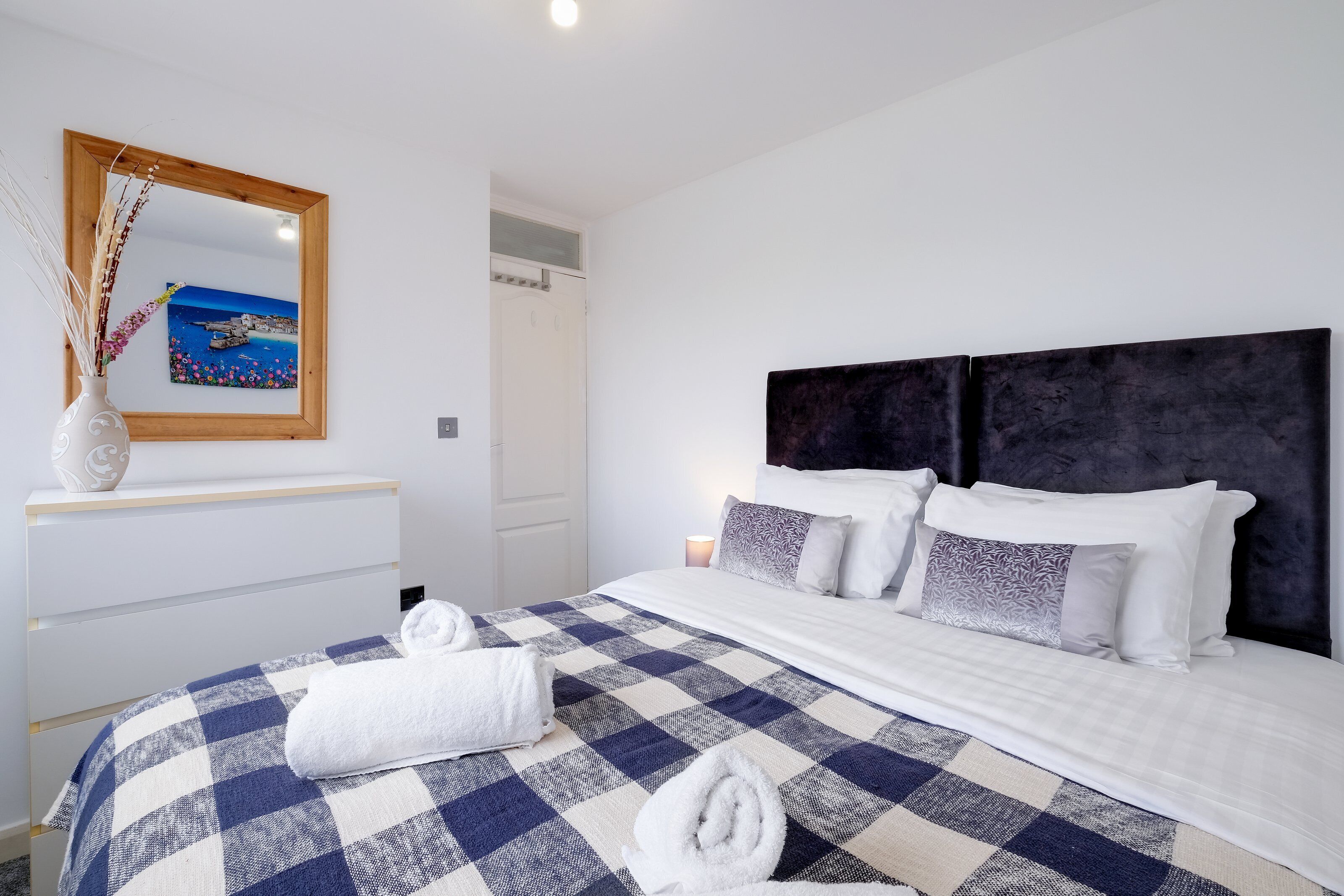A neatly made bed with a checkered bedspread, a headboard, and two pillows.