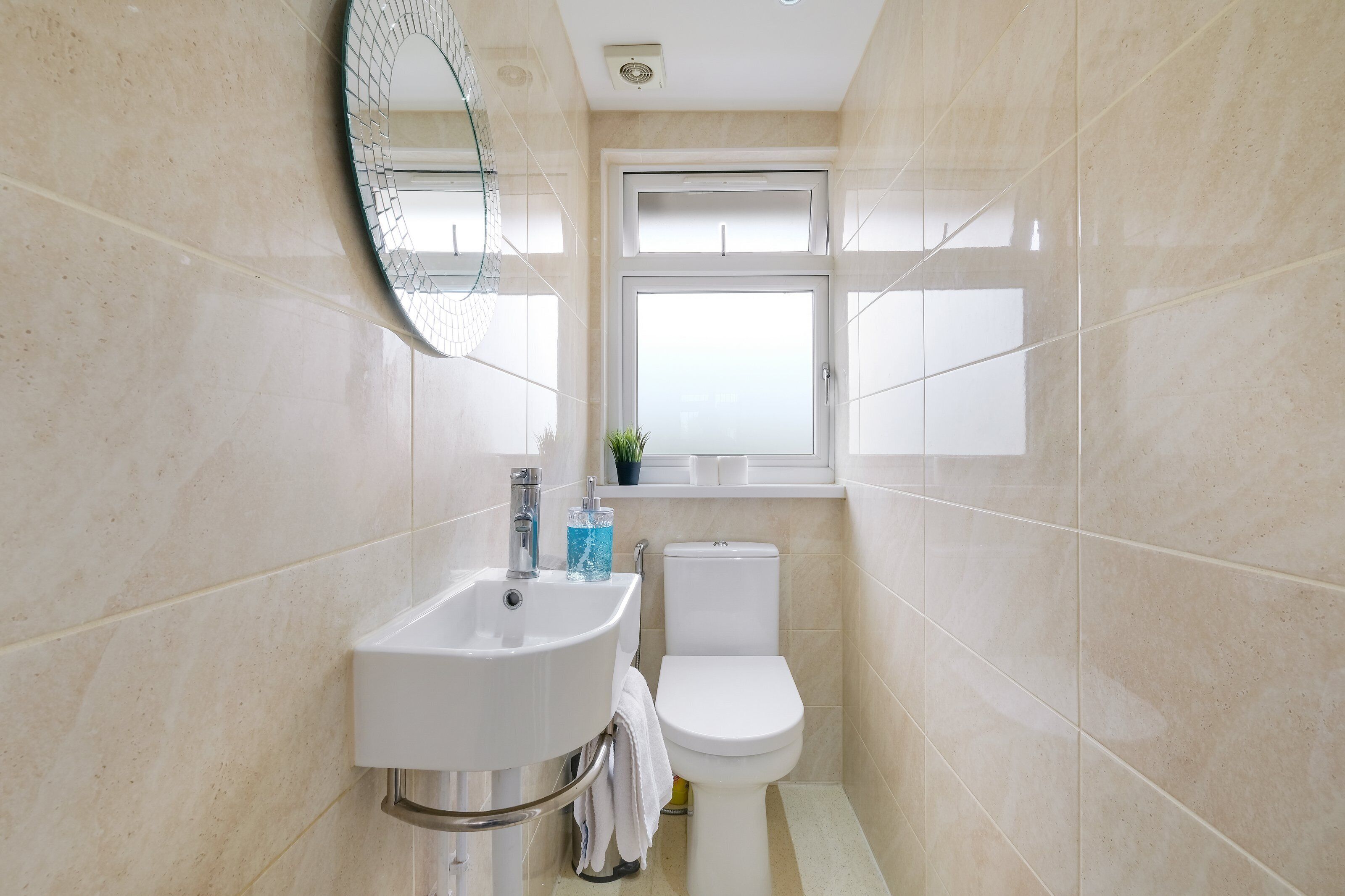 Une salle de bain avec un lavabo, des toilettes et une fenêtre située au-dessus des toilettes.