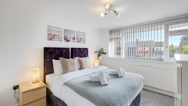 A modern bedroom with a bed, bedside tables, and artwork on the wall. -  Elegant 5BR Home with Free EV Charger, Garden and Parking (Slough)