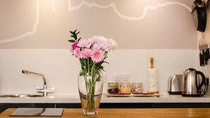 A kitchen with a vase of flowers on the counter, a knife block, and a kettle.