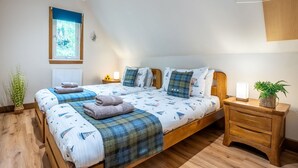 Une chambre avec un lit en bois, une table de chevet, un portant à vêtements et une fenêtre donnant sur un paysage verdoyant.