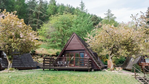 Une cabane avec un toit en pente, une terrasse en bois et une fenêtre.