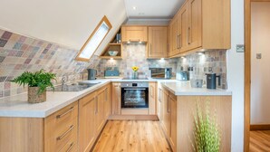 Une cuisine moderne avec des meubles en bois, un four encastré, un four à micro-ondes et une machine à café.