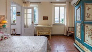 Een slaapkamer met een bed, een dressoir, een bureau en twee ramen.