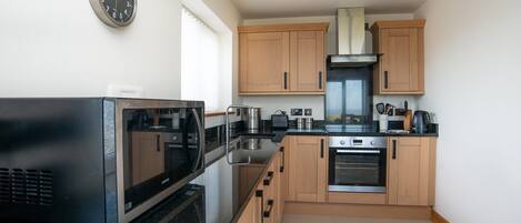 A compact kitchen with a microwave, stove, and wooden cabinets.