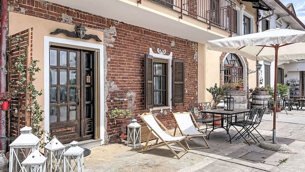 A building with a brick facade, large windows, and a balcony with outdoor furniture. - Nice apartment for 6 people with WIFI, TV, patio and panoramic view (Asti)