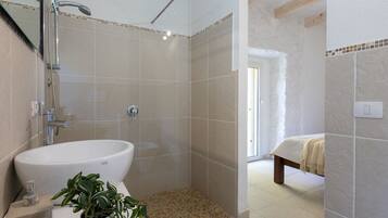 Une salle de bain moderne avec un grand lavabo, une douche et un petit banc.