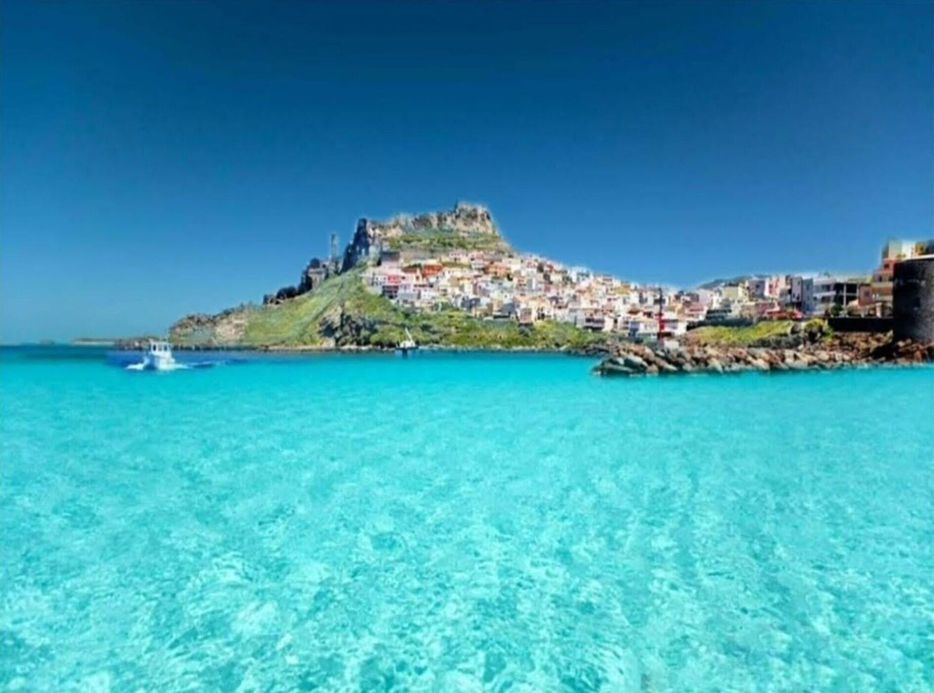 A coastal town with a prominent hilltop structure, clear turquoise waters, and a small boat in the foreground.