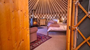 A yurt interior with a bed, a small wooden cabinet, a heater, and a rug. - Chalet With Gleneagles Views, hot Tub, No Deposit (Auchterarder)