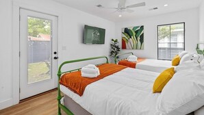 Une chambre d’hôtel avec deux lits, un ventilateur de plafond, une télévision et des œuvres d’art accrochées aux murs.