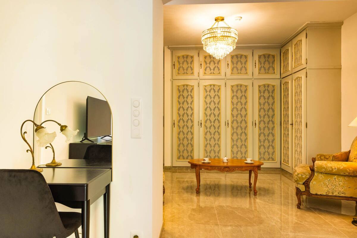 A room with a desk, a chair, a table with cups, a sofa, and a wardrobe with patterned doors.