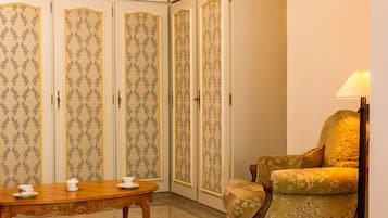 Una habitación con una mesa de madera, un sofá, una araña y papel tapiz estampado.