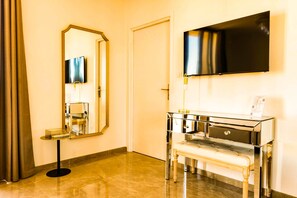 A hotel room with a large mirror, a flat-screen TV mounted on the wall, a vanity with a mirror, and a bench. - Hotel Villa Martini (Ajaccio)