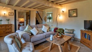 A cozy living room with a sofa, a coffee table, a television, and a bookshelf.