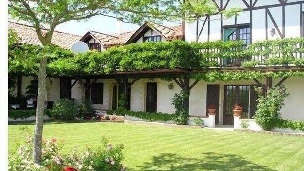 A traditional house with a well-maintained garden, a clear lawn, and a wooden balcony. - LPMDC - A haven of charm and authenticity in the heart of nature (Salerm)