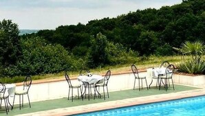 A swimming pool with a table and chairs set up for dining, surrounded by greenery and a cloudy sky. - LPMDC - A haven of charm and authenticity in the heart of nature (Salerm)