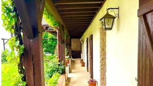 A covered corridor with potted plants and a stone floor, leading to a door. - LPMDC - A haven of charm and authenticity in the heart of nature (Salerm)