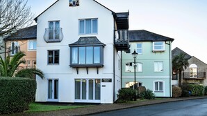 A two-story building with a balcony, a sign reading 'Tregenn Court,' and a street view with other buildings. - Apartment in Falmouth Near Beaches & Harbour (Falmouth)