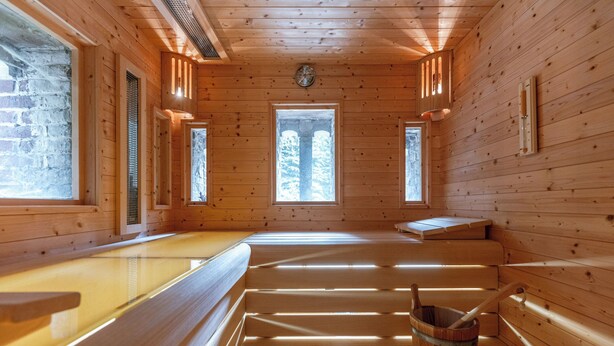 Ein Saunaraum mit Holzwänden, Bänken und einem Holzfass.
