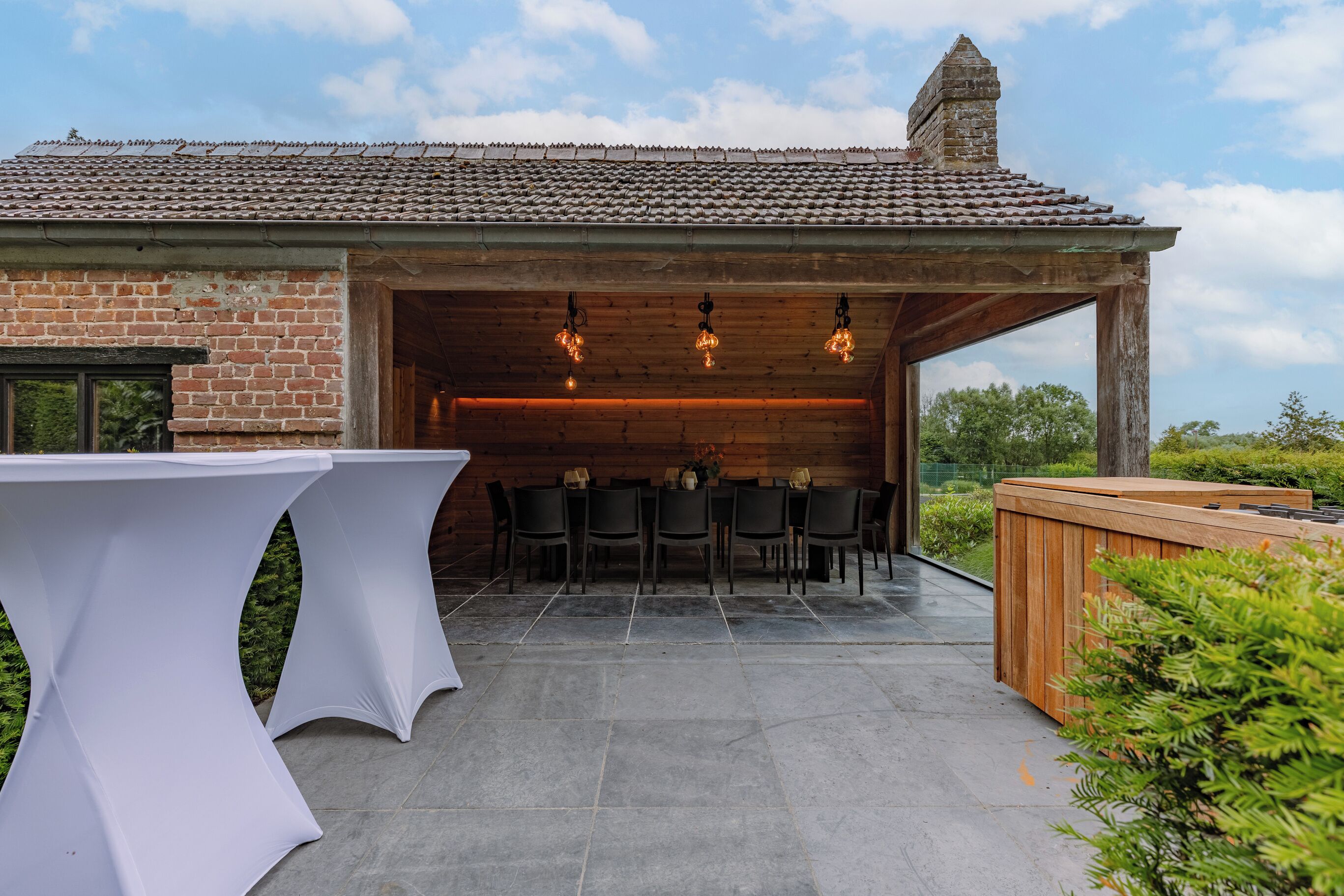 An outdoor patio with a brick wall, a wooden table, and a wooden bench.