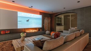 Ein modernes Wohnzimmer mit großem Fernsehbildschirm, Kamin, Sofa und Couchtisch aus Holz.