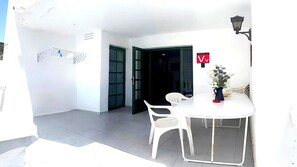 A white room with a round table and two chairs, a door, and a wall-mounted light fixture. - Apartment Florencia With Pool & Wifi in Puerto del Carmen, Lanzarote (Tías)