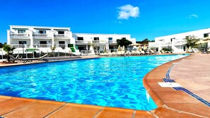 A swimming pool with a clear blue water surface, surrounded by a tiled deck and lounge chairs. - Apartment Florencia With Pool & Wifi in Puerto del Carmen, Lanzarote (Tías)