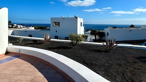 A rooftop terrace with a view of the sea, white buildings, and some vegetation. - Apartment Florencia With Pool & Wifi in Puerto del Carmen, Lanzarote (Tías)