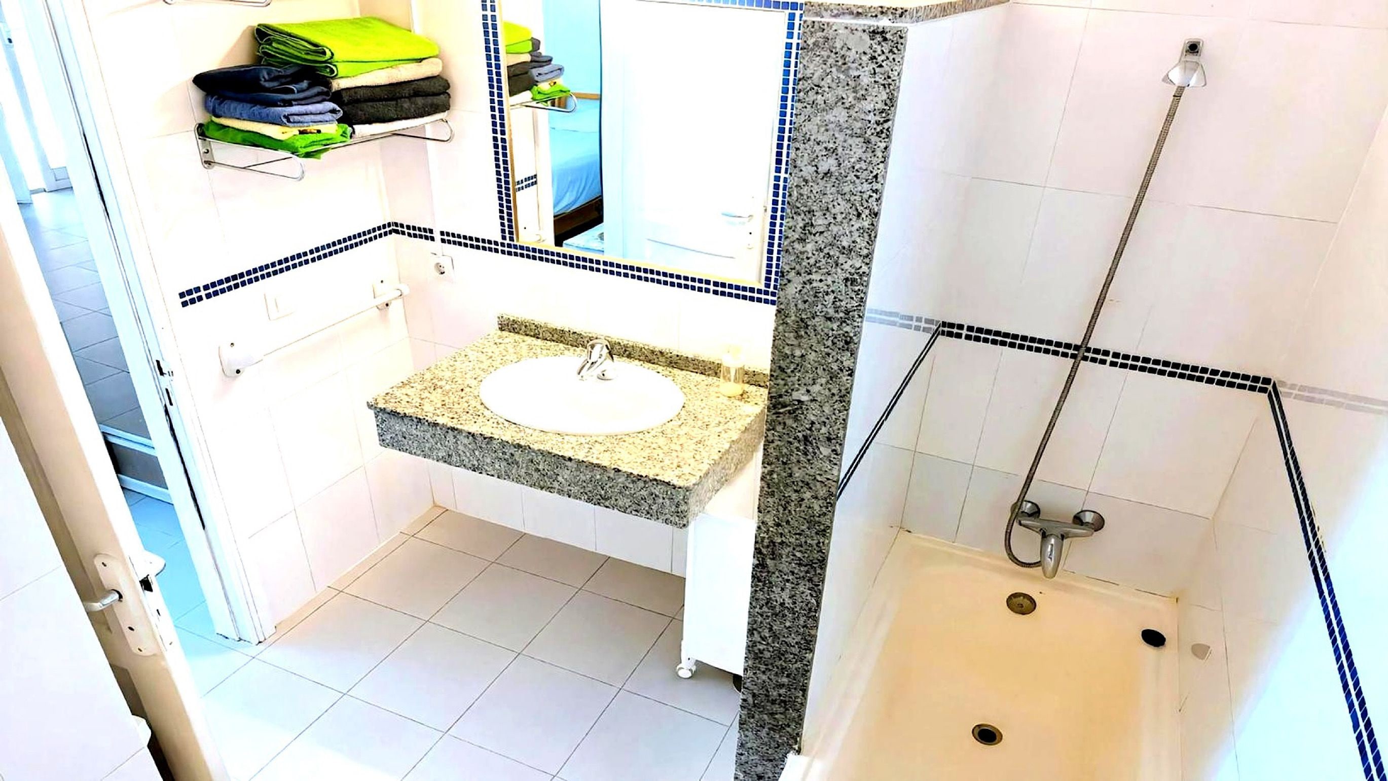 Ein Badezimmer mit Waschbecken, Dusche und Handtuchhalter mit gefalteten Handtüchern.