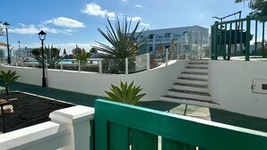 A pool area with steps leading to a building, surrounded by plants and a clear sky. - Apartment Florencia With Pool & Wifi in Puerto del Carmen, Lanzarote (Tías)