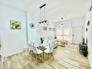 A modern living room with a glass dining table, white sofas, and a wooden floor. - Prague Bridge Aparment (2-bedroom apartment) (Madrid)