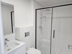 A modern bathroom with a glass shower enclosure, a white sink, and a mirror. - Beautiful apartment Lotos with veranda and view to big pool. (Jávea)