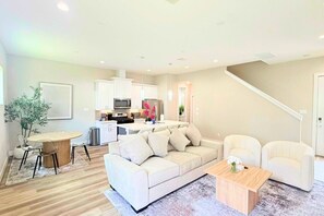 Ein modernes Wohnzimmer mit Sofa, Couchtisch und Essbereich.