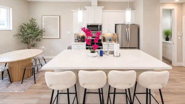 A modern kitchen with white cabinets, stainless steel appliances, and a central island with bar stools.