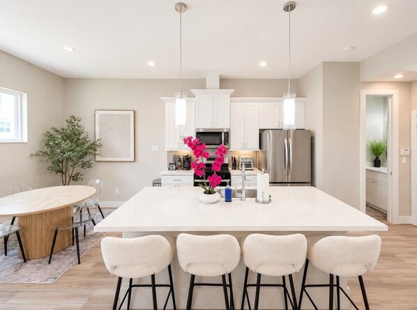 A modern kitchen with white cabinets, stainless steel appliances, and a central island with bar stools.