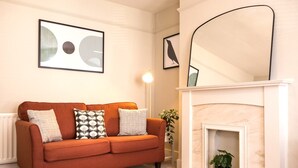 A living room with a sofa, a fireplace, and framed artwork on the wall.