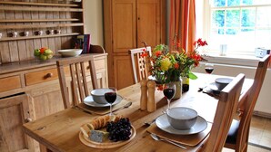A wooden dining table set with plates, bowls, and a fruit platter. - Cottage in North York Moors Near Manor House (Middlesbrough)