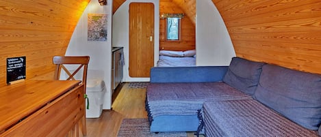 Un dormitorio acogedor en el ático con paredes de madera, una cama, un sofá y un escritorio pequeño.