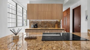 Una cocina moderna con encimeras de granito, armarios de madera y estufa integrada.