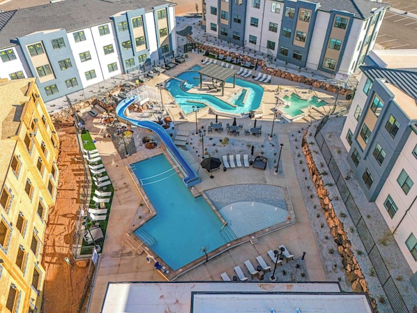 An aerial view of a hotel with multiple swimming pools, sun loungers, and outdoor seating areas.