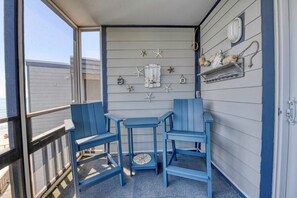 A balcony with blue chairs and a small table, decorated with starfish and a sign reading 'HMS Pandora.'