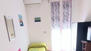 A bedroom with a bed, a chair, a small table, and a window with curtains. - Fabulous apartment, sea view ideal for families & groups of friends. (Augusta)