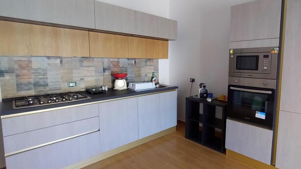 A modern kitchen with a gas stove, microwave, and oven, light-colored cabinets, and a tiled backsplash. - Fabulous apartment, sea view ideal for families & groups of friends. (Augusta)