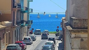 A narrow street with parked cars and a view of the sea. - Fabulous apartment, sea view ideal for families & groups of friends. (Augusta)