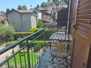 A balcony with wooden benches, a stone wall, and a view of surrounding houses. - Sormano 2 - THE V Collection Apartment by OGS (Sormano)