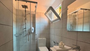 A modern bathroom with a glass shower enclosure, a toilet, and a large sink with a mirror above. - Sormano 2 - THE V Collection Apartment by OGS (Sormano)