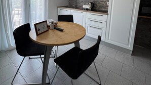 A modern kitchen with white cabinets, a round wooden table, and black chairs. - Sormano 2 - THE V Collection Apartment by OGS (Sormano)